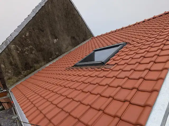Toiture neuve en tuiles avec fenêtre de toit et rives en zinc